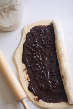 a pastry with chocolate spread on it next to a rolling pin