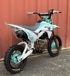 a dirt bike parked in front of a red wall