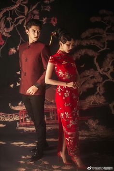 a man and woman dressed in traditional chinese clothing standing next to each other on a dark background