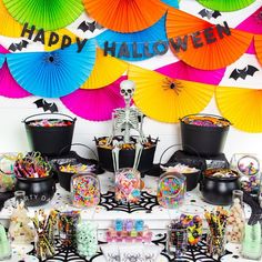 a table topped with lots of halloween decorations and paper parasols above it is a skeleton