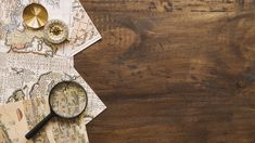 an old map, magnifying glass and other items on a wooden table