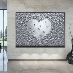 a large metal heart on a wall in a living room with vases and artwork