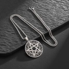 a pentagramil pendant is shown on a black surface with silver beads and chains