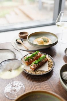 a table topped with plates and glasses filled with food next to wine glasses on top of a wooden table