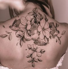 the back of a woman's shoulder with flowers and birds on her upper back