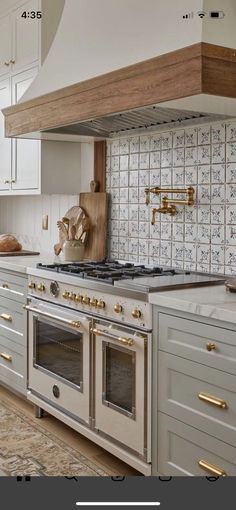 an image of a kitchen setting with white cabinets and gold pulls on the oven hood