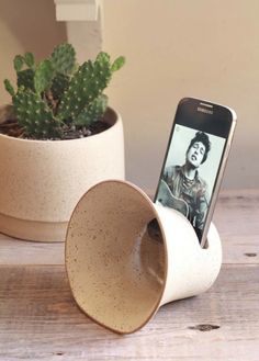 a cell phone sitting in a cup on top of a table next to a plant