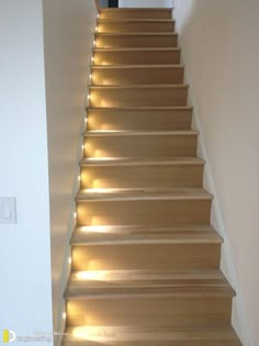 a set of stairs with lights on the bottom and bottom, leading up to an open door