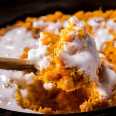 a spoonful of food is being lifted from a casserole dish with white icing