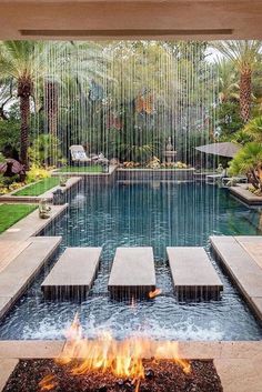 a fire pit in the middle of a yard with water flowing from it and umbrellas hanging over it