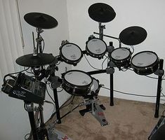 a set of electronic drums sitting on top of a carpeted floor next to a wall