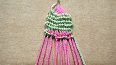 a pink and green crocheted object on top of a brown surface with a wooden handle