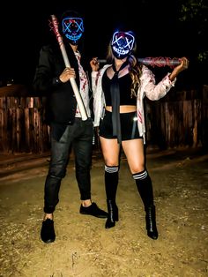 two people dressed up in costumes and holding baseball bats, standing next to each other