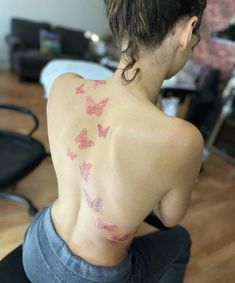 the back of a woman's upper body with pink butterflies on her left shoulder