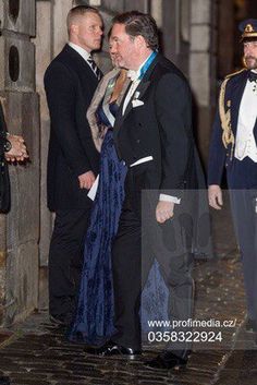 two men in formal wear standing next to each other on the street at night time