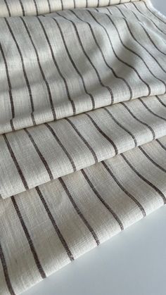 three pieces of fabric sitting on top of a white tablecloth covered in brown and black stripes