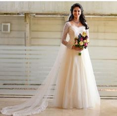 a woman in a wedding dress standing next to a garage door holding a bouquet of flowers