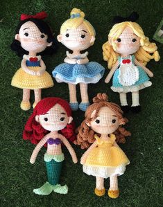 four crocheted dolls sitting on top of the grass in front of each other