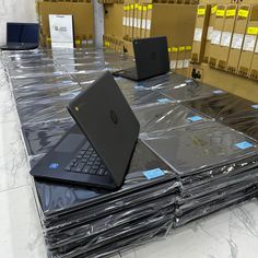 several laptops are sitting on top of plastic wrapped boxes in a storage area at a computer store