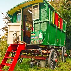 a green and red train car sitting in the grass