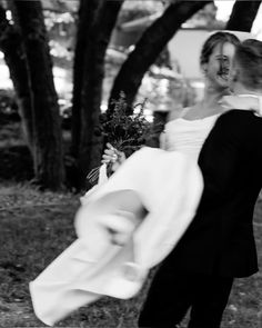 a bride and groom are walking through the park