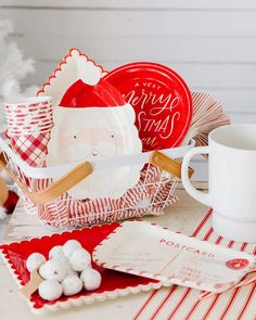 a table topped with plates and cups next to a cup filled with marshmallows