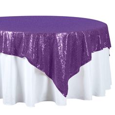 a purple and white table cloth on top of a round table with sequins