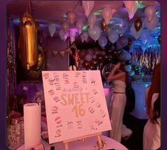 there is a sign that says sweet sixteen and balloons are in the air behind it