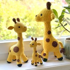 two crocheted giraffes and a baby giraffe on a window sill