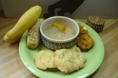 a green plate topped with different types of food on top of a wooden table next to a banana