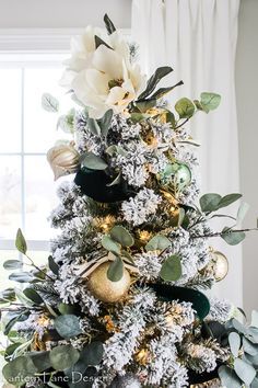 a decorated christmas tree with white flowers and greenery