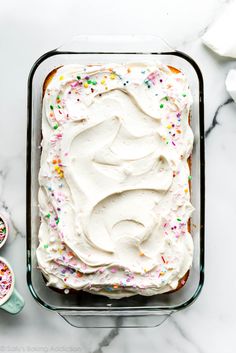 a cake in a pan with white frosting and sprinkles