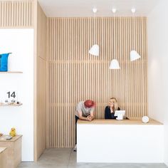 two people sitting at a counter in a room with wood paneling on the walls