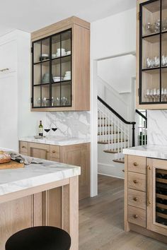 a kitchen with wooden cabinets and marble counter tops, white walls and wood flooring