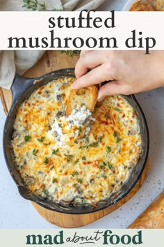 a person dipping some food into a skillet with cheese and herbs on top, in front of other dishes