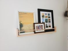 three framed pictures are hanging on a wall above a wooden shelf with rope and hooks