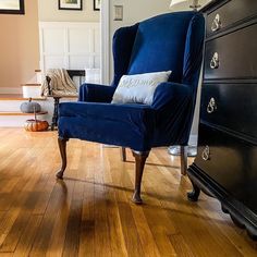 a blue chair sitting on top of a hard wood floor next to a black dresser