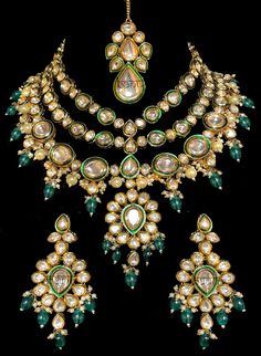 Ariana - Modern Kundan Bridal Jewelry with Pearls, Meenakari & Emeralds Contemporary Indian bridal set makes every bride's outfit perfect. This Kundan stone setting jewelry set is accented with gorgeous Polki gemstones making it one of a kind. Stunning emerald drops adorn this beautiful choker & earrings. It is further accented with extraordinary luxury pearl drops. This jewelry set is sure to make you stand out from the crowd with its elaborating green outline like Meenakari handwork. This chok Festive Kundan Emerald Necklace With Intricate Design, Chandbali Emerald Necklace With Meenakari For Celebration, Chandbali Meenakari Emerald Necklace For Celebration, Emerald Chandbali Necklace With Meenakari For Festivals, Festive Emerald Chandbali Necklace With Meenakari, Festive Meenakari Emerald Chandbali Necklace, Kundan Emerald Chandbali Necklace For Gift, Emerald Kundan Necklace With Meenakari For Gift, Chandbali Emerald Kundan Necklace As Gift