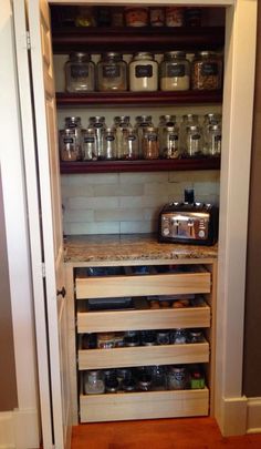 an open pantry with lots of jars and pans on the shelves next to each other