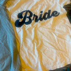 a white shirt with the word bride printed on it sitting on top of a bed