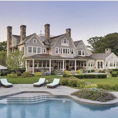 a large house with a pool in front of it and some lawn chairs around the pool