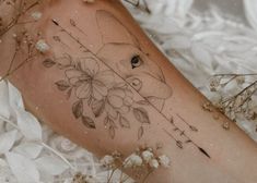 a woman's leg with flowers and an arrow tattoo on her left side thigh