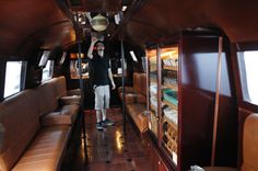 a man standing in the aisle of a train car with leather couches and shelves