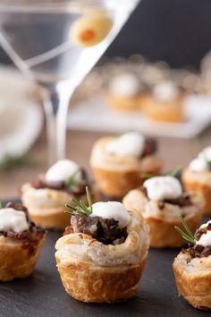 small appetizers are arranged on a table with a wine glass in the background