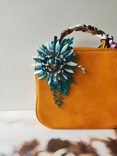 an orange purse with a blue flower on the front and green leaves on the back