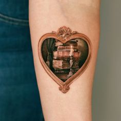 a woman's arm with a heart shaped frame and books on it