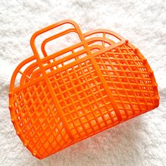 an orange plastic basket sitting on top of a white carpeted floor next to a cell phone