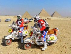 two men riding motorcycles in front of the pyramids