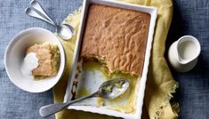 a cake in a pan and two bowls with spoons next to it