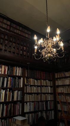 a chandelier hanging from the ceiling in front of a bookcase filled with books